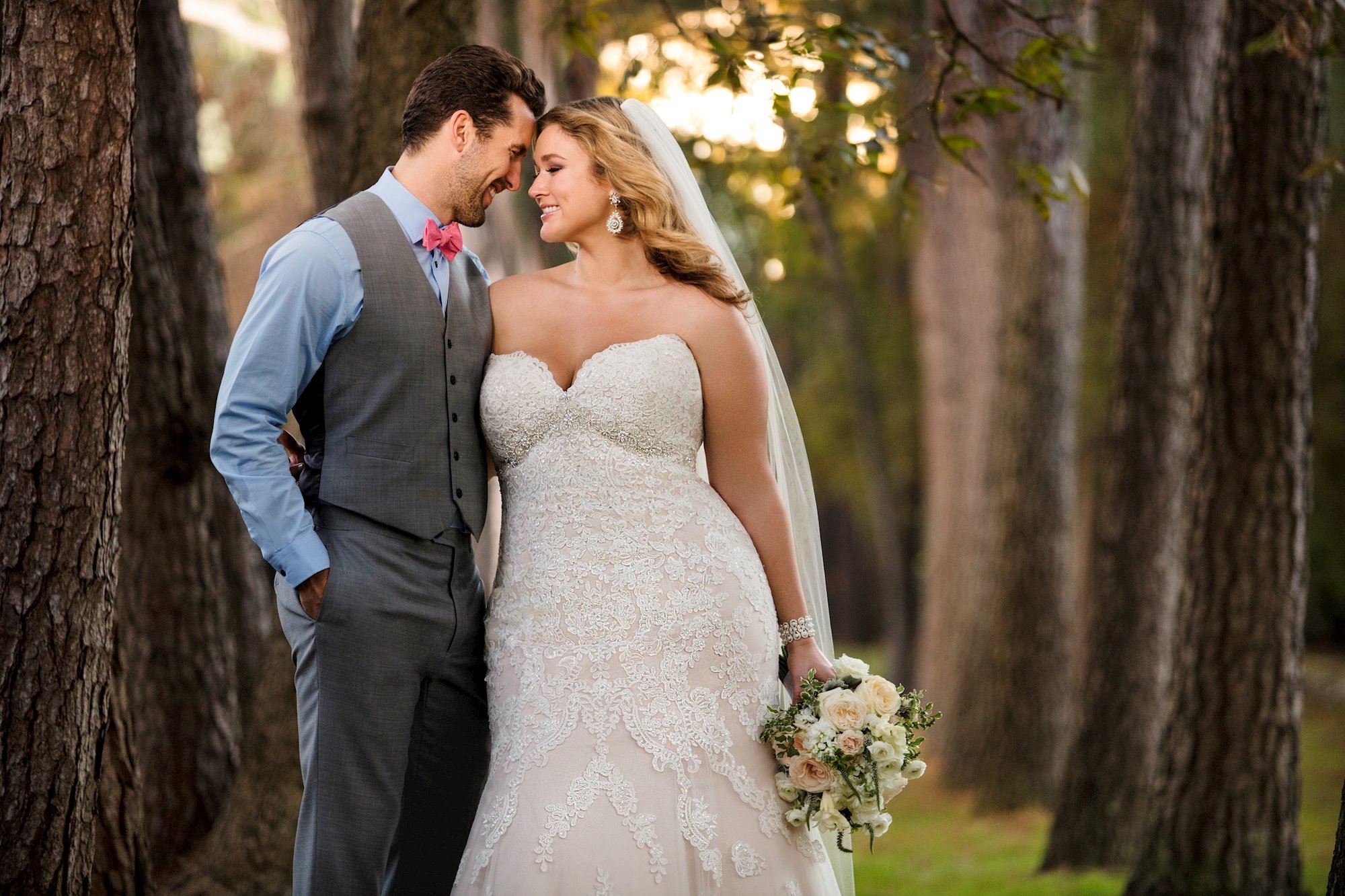 Groom in vest and blonde bride in white bridal dress holding flowers